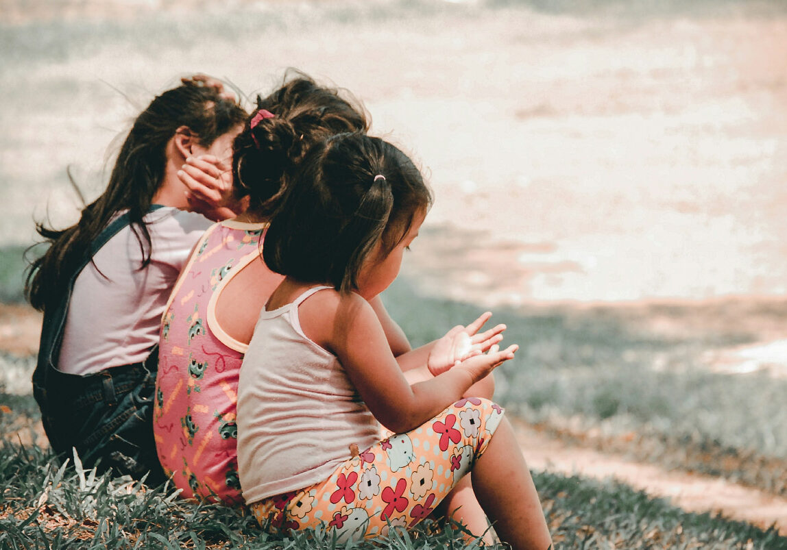 Drie kleine kinderen zitten in het gras