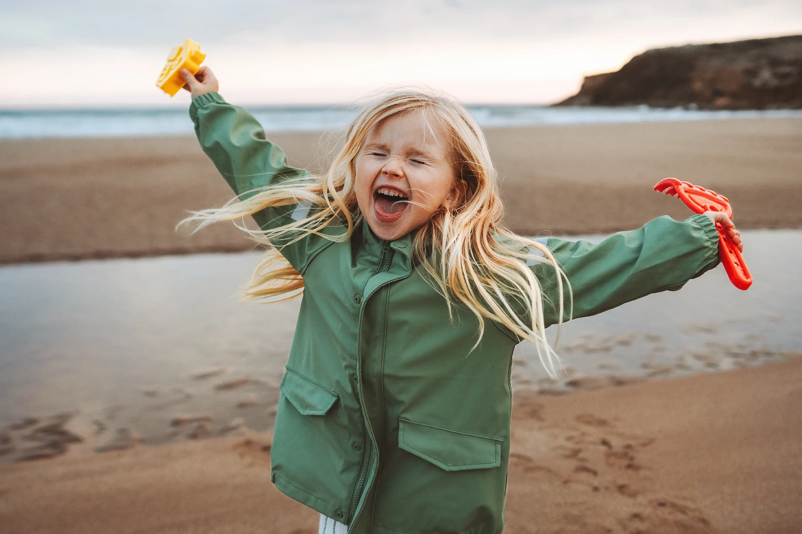 Meisje gelukkig lachen spelen buiten familie levensstijl vakanties emotioneel kind glimlachend wandelen met speelgoed op het strand